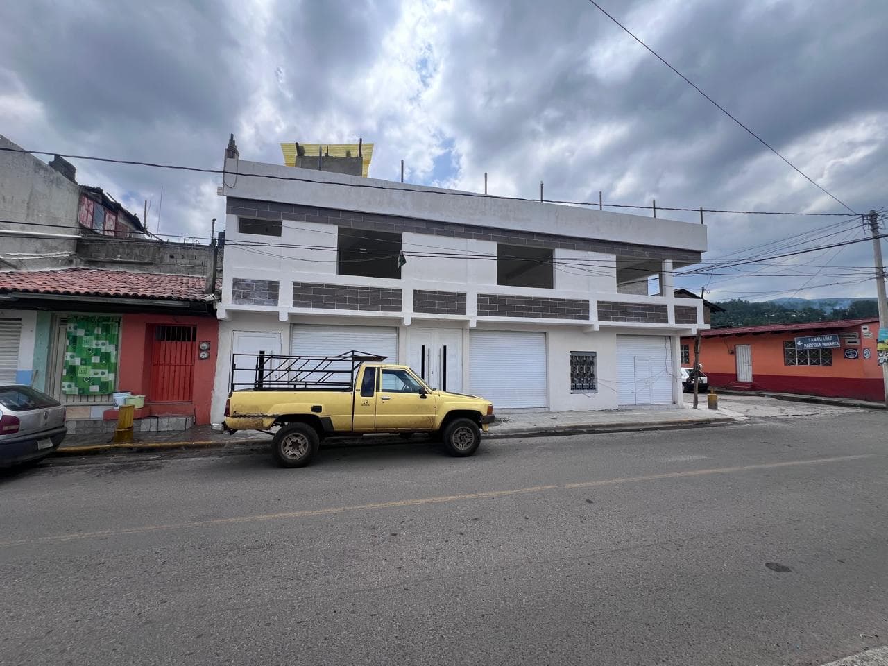Vista frontal general de una construcción de uso mixto con locales en planta baja y un nivel residencial superior.